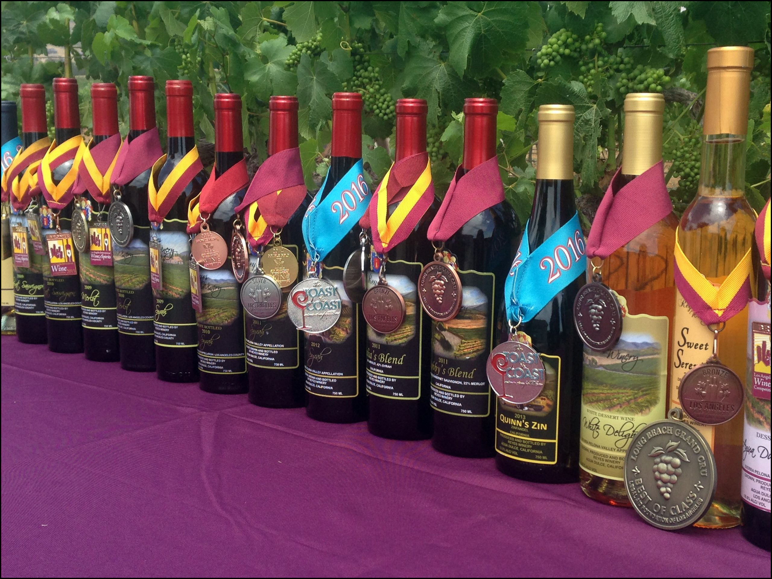 A group of bottles with a large number of awards draped over them.