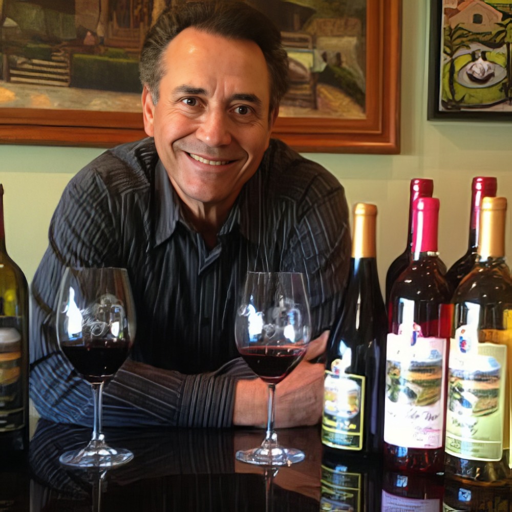 Owner of the Reyes Winery smiling behind several bottles of his wine.